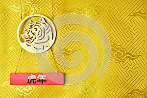 Gold tiger symbol on yellow fabric with traditional chinese ornament with clouds. Copyspace. Chinese New Year of the Tiger 2022.