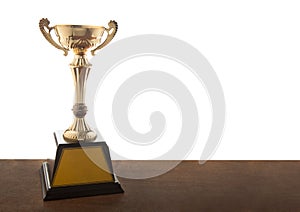 Gold trophy on wooden table isolated over white background. Winning awards with copy space