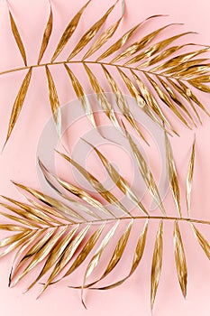 Gold tropical palm leaves on pink background. Flat lay, top view minimal concept.
