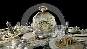 Gold vintage pocket watch dial on pile of clockwork parts. Round old clock among metal gears, springs and cogwheels