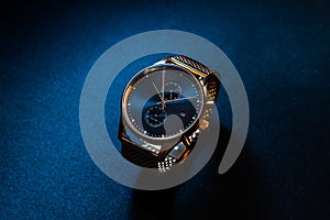 Gold watch on darkblue background photo