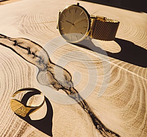 Gold watch and signet on wooden background
