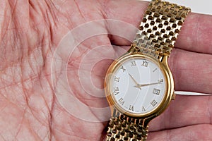 Gold watch with white face in palm of hand