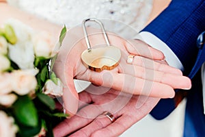 Gold wedding lock in the form of heart in the hands