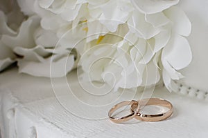 Gold wedding rings on a background of white decorative flowers