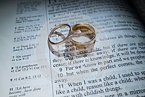 Gold Wedding Rings on a Bible with the Scripture Love Never Fails