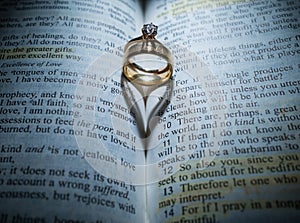 Gold Wedding Rings in the Center of the Bible Forming a Heart with the Shadow