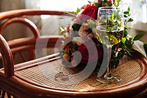 Gold wedding rings, a glass of champagne, bouquet on the table