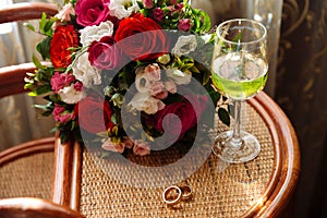 Gold wedding rings, a glass of champagne, bouquet on the table