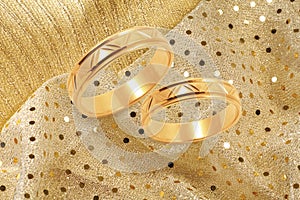 Gold wedding rings on golden festive background