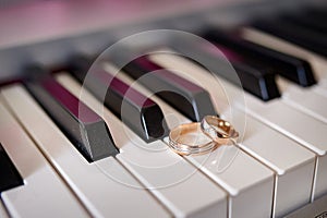 Gold wedding rings lie on the piano keys
