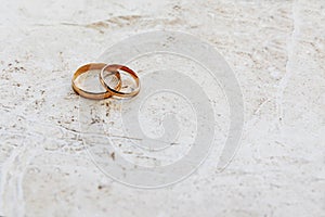 Gold wedding rings lie on a stone background