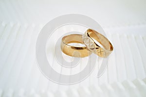 Gold wedding rings on light ribbon background