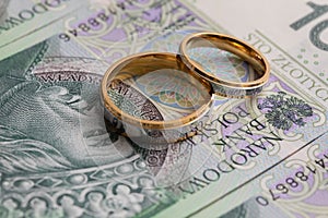 Gold wedding rings surrounded by a stack of Polish banknotes