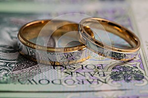 Gold wedding rings surrounded by a stack of Polish banknotes