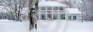 Gold and white front door decorated with Christmas decorations and snow