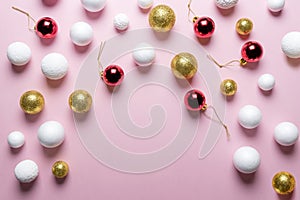 Gold and white glitter ball decoration with red Christmas bauble on pink background.