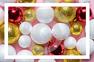 Gold and white glitter ball decoration with red Christmas bauble on pink background.