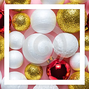 Gold and white glitter ball decoration with red Christmas bauble on pink background.