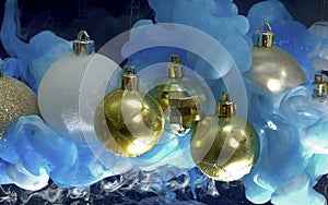 Gold, white and silver shiny Christmas balls. Blue and white ink in the water