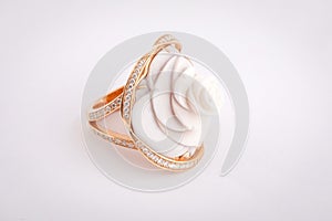 Gold women`s ring with white stone in the shape of a rose, with a border of white diamonds isolated on a white background.