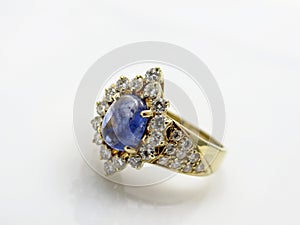 Gold womens ring with diamonds and a blue gem in the form of a flower on a female hand on a white background photo