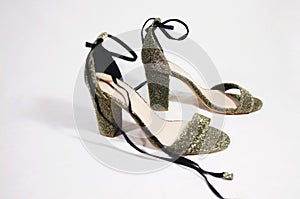Gold womens sandals. Girls shoes on a heel in gold color with lacing. Close up photo on a white background