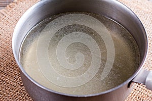 Gold yellow bouillon in a saucepan on a wooden table