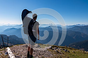 Goldeck - Man with baby carrier looking at magical mountain peaks of Karawanks and Julian Alps seen from Goldeck