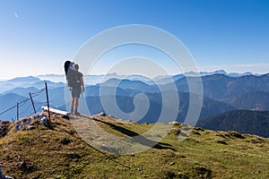 Goldeck - Man with baby carrier looking at magical mountain peaks of Karawanks and Julian Alps seen from Goldeck