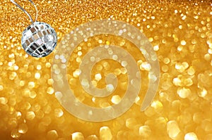 Golden abstract bokeh lights and miniature glitter ball. party or music concept.