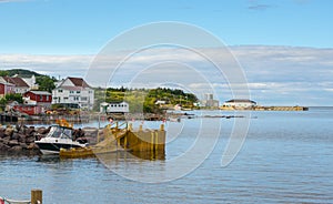 Golden adirondack chairs on a rock jetty. Houses on the sea along a village shoreline.