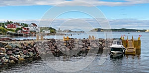 Golden adirondack chairs on a rock jetty. Houses on the sea along a village shoreline.