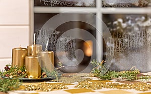 Golden Advent candles on a table in front of a window in winter weather, hoarfrost