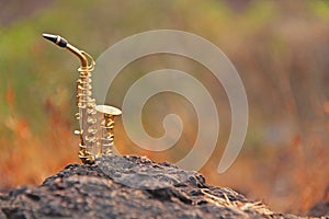 The golden alto saxophone stands on a black stone. Romantic musical background. Musical cover and creative