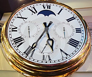 Golden analogue clock with roman numerals and calendar time of day letters