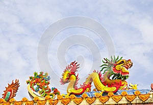 Golden artistic grand yellow Asian dragon statue on the roof of a temple