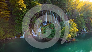 Golden autumn nature in Plitvice Lakes National Park Croatia. Waterfall in forest with colorful trees and emerald green