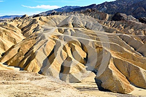 Golden badlands eroded into waves, pleats and gullies at Zabriskie Point in the Death Valley National Park