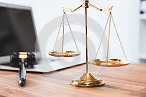 Golden balanced scale and gavel on desk with laptop in law office. equility