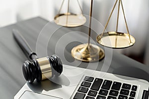 Golden balanced scale and gavel on desk with laptop in law office. equility