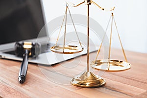 Golden balanced scale and gavel on desk with laptop in law office. equility