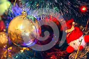 Golden ball and knitted toy hang on a green Christmas tree