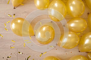 Golden balloons and confetti on a wooden floor. preparation for a birthday or other party