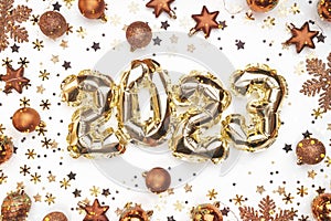 Golden balloons numbers of year 2023. Glowing festive garland with bronze toys, stars and snowflakes on white background