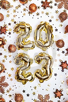 Golden balloons numbers of year 2023. Glowing festive garland with bronze toys, stars and snowflakes on white background