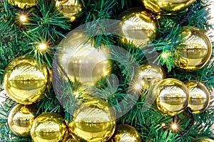 Golden balls and baubles hanging as decorations on a Christmas tree, close-up