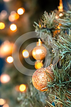 Golden balls and bokeh lights on a green Christmas tree, winter background for greeting card, atmosphere of cosiness and