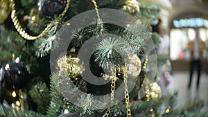 Golden balls and chains. New Year`s and abstract blurred shopping mall background with Christmas tree decorations.