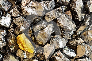 Golden bar on background of raw coal nuggets close-up